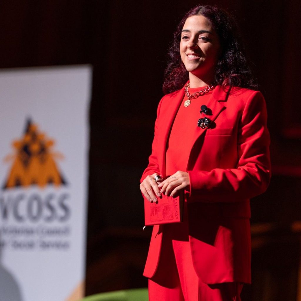 Wren Rapture - a smiling woman standing on stage in a red suit